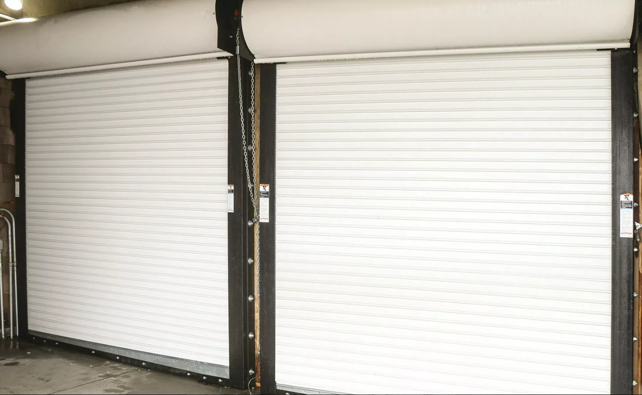 Modern commercial garage door at a business in Baltimore, OH, showcasing pristine condition and company logo with a well-lit entrance