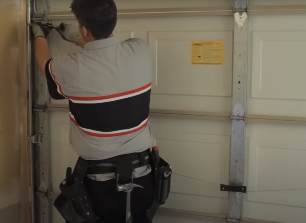 Professional technician repairing a garage door panel, focusing on the restoration process with tools in use in Baltimore, OH