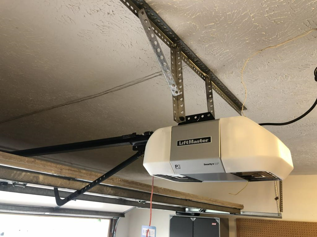 Professional technician installing a garage door opener in a residential home in Baltimore, OH, demonstrating precision workmanship and modern equipment.